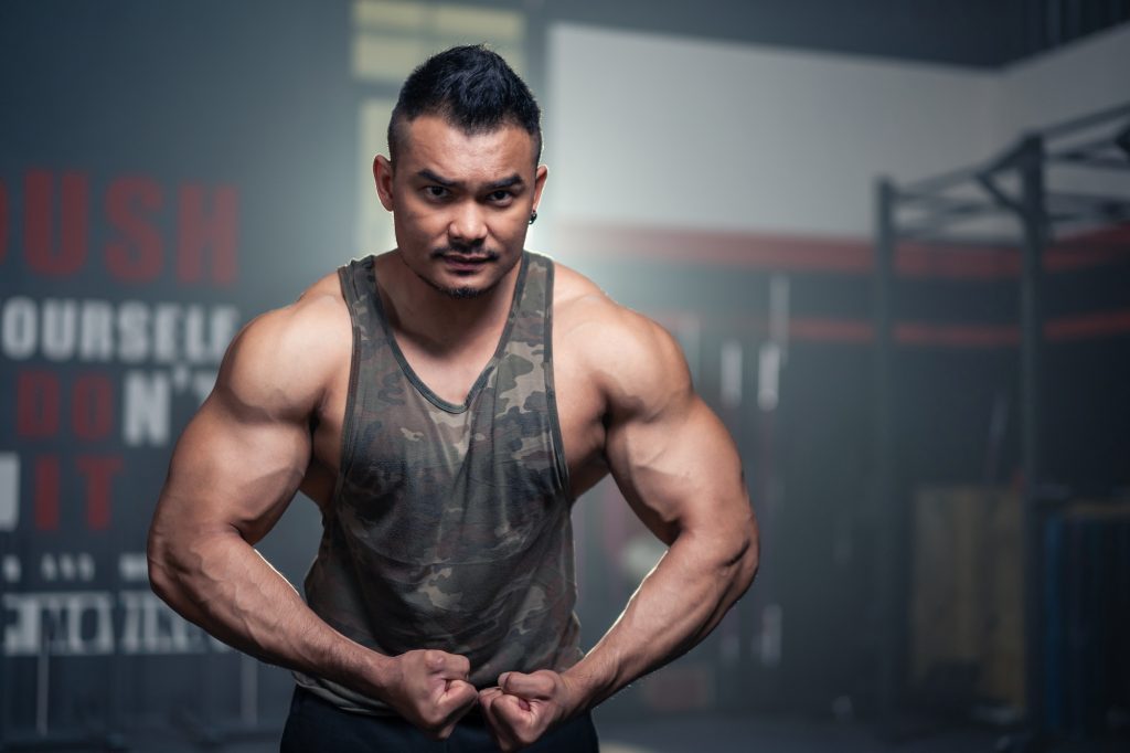Portrait of Active healthy sport man showing muscles and biceps on arms.