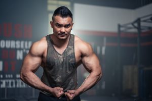 Portrait of Active healthy sport man showing muscles and biceps on arms.