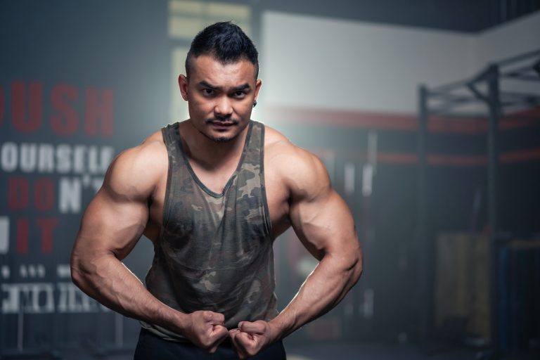 Portrait of Active healthy sport man showing muscles and biceps on arms.
