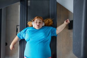 Sad unhappy overweight woman feeling pain while training at wall for posture correction