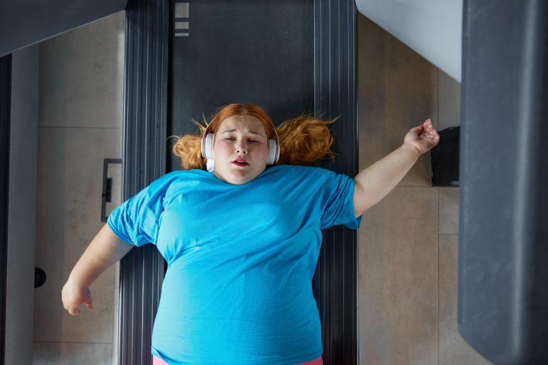 Sad unhappy overweight woman feeling pain while training at wall for posture correction