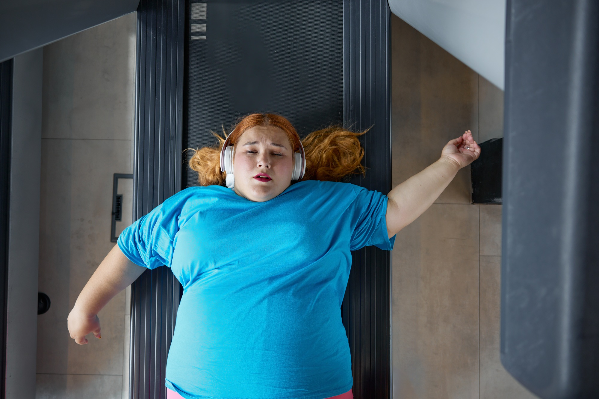 Sad unhappy overweight woman feeling pain while training at wall for posture correction