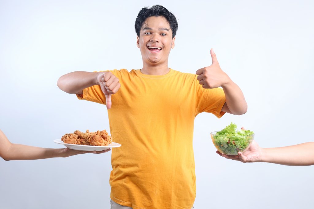 Young Asian Man Showing Good Fod And Bad Food