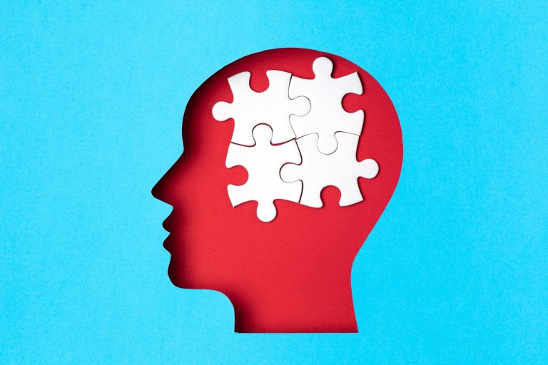 Papercut head with jigsaw puzzle pieces inside. Mental health problems, psychology, memory, logic
