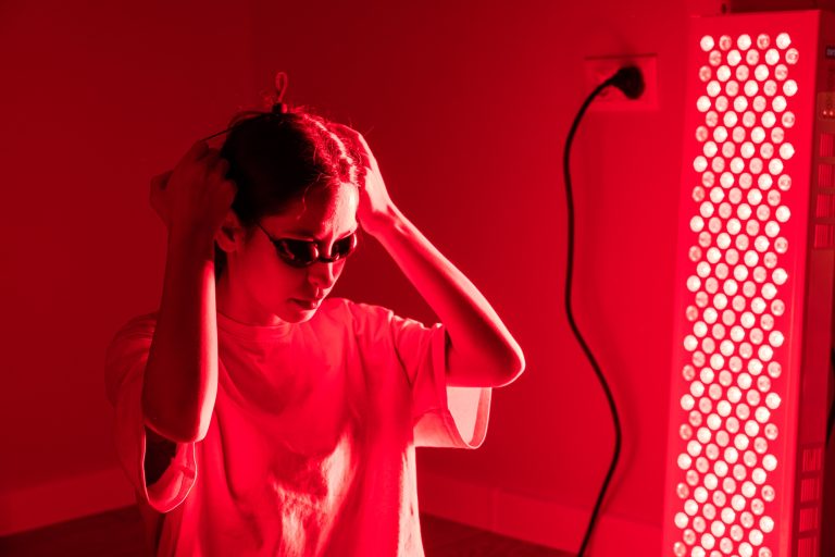 Woman adjusting protective glasses during red light therapy